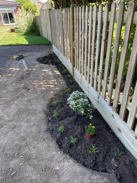 Freshly planted border along a wooden fence
